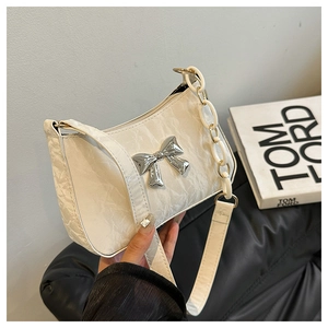 Détail du sac à bandoulière blanc crème plissé avec nœud argenté et chaîne