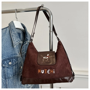 Detail of a brown suede shoulder bag featuring a cute dog embroidery and MUTEHI text