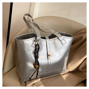 Sac fourre-tout argenté métallisé avec fermoir doré sur une chaise en tissu beige