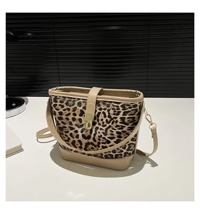 Detail of leopard print bucket bag with beige trim and golden twist lock on white desk