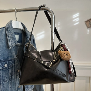 Vintage black tote bag with strap detail, bear pendant and silk scarf on display