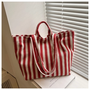 Détail d'un sac cabas en toile à rayures rouges et blanches sur un rebord de fenêtre