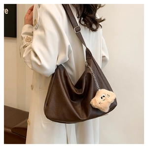 Detail of dark brown faux leather hobo bag with adjustable strap and star plush pendant
