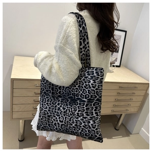 Detail of large leopard print tote bag showing texture and size on a model