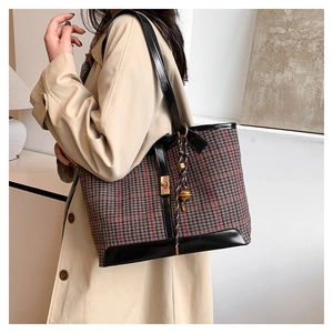 Detail view of vintage houndstooth tote bag with leather trim and tassel charm
