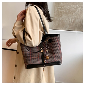 Detail view of retro houndstooth tote bag with leather trim and gold metal buckle