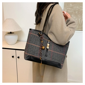 Detail of vintage houndstooth tote bag with leather straps and golden bell charm