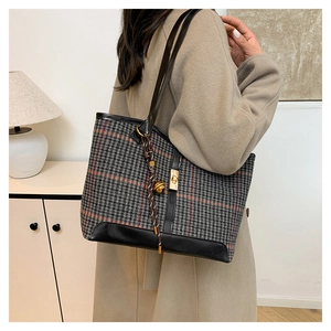 Close-up of houndstooth tote bag with leather straps and golden bell charm detail