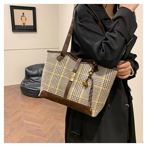 Detail view of vintage houndstooth tote bag with brown leather accents and gold hardware