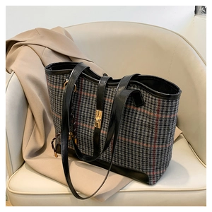 Detail of houndstooth tote bag with golden twist lock and leather handles on beige seat