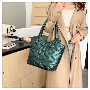 Borsa tote trapuntata verde scuro metallizzato mostrata in un elegante caffè set
