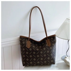 Detailed close-up of brown monogram tote bag with leather straps and geometric pattern