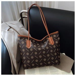 Detail of the large brown monogram tote bag styled with a gray suit on a black chair