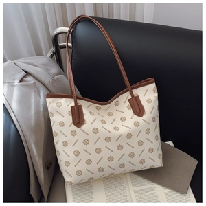 Detail view of a large printed tote bag featuring brown floral patterns on a cream base