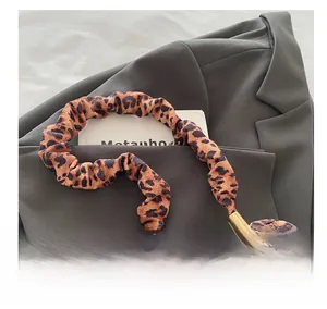 Close-up of leopard print scrunchie handle with gold metal clips on a brown blazer