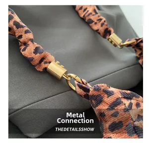Close-up of golden metal buckle connecting leopard print strap on shoulder bag