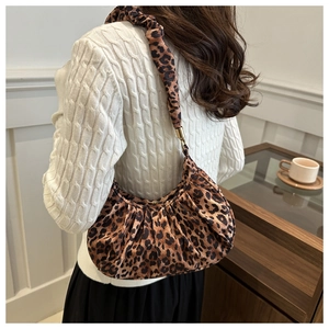 Model wearing a vintage leopard print pleated crescent shoulder bag in a cozy indoor setting