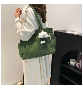 Detail of dark green corduroy tote bag featuring soft texture and white cloud pendant