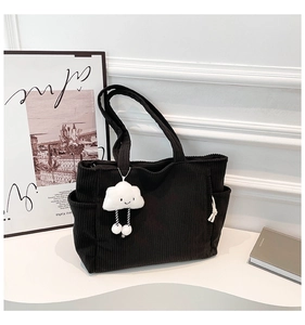 Detail of black corduroy tote bag with vertical texture and white cloud plush charm