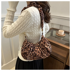 Detail of leopard print crescent bag with ruched fabric strap and gold metal hardware