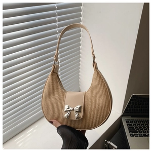 Detail shot of beige crescent bag featuring ruched texture and silver bow buckle