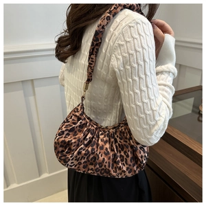 Detail of leopard print crescent bag with gold hardware worn by a model in a knit sweater