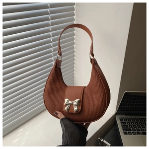 Detail of caramel crescent shoulder bag with pleated texture and silver bow buckle