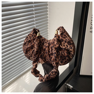 Detail of leopard print handbag featuring ruched fabric texture and golden rings