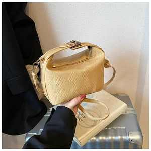 Close-up of beige woven texture and gold twist lock on stylish crossbody bag