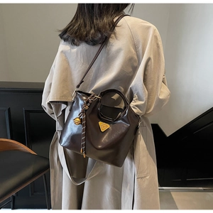 Details der dunkelbraunen Retro-Tasche aus Kunstleder mit Golddreieck und Glockendeko