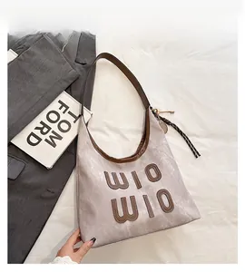 Close-up of beige Hobo bag featuring brown leather trim and WIO WIO letter appliqué