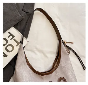 Close-up of canvas tote bag with brown leather trim and tennis racket keychain detail