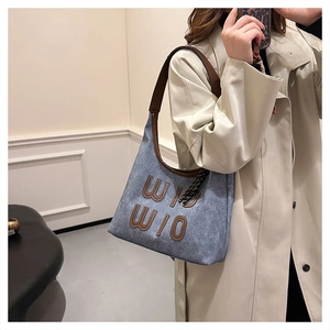 Vue détaillée du sac cabas en denim bleu clair avec écussons et liserés en cuir marron