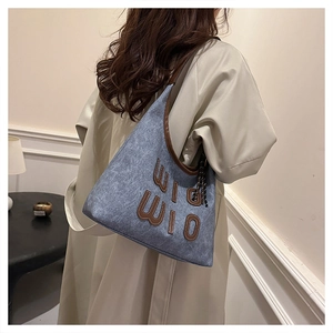 Detail of blue denim shoulder bag with brown leather trim and WIO WIO embroidery