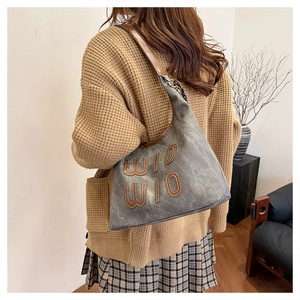 Détail du sac hobo en toile grise avec patch WIO WIO et bandoulière chaîne cuir marron
