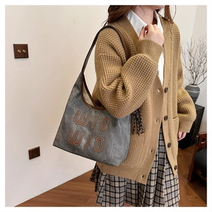 Detail of vintage gray tote bag with brown leather trim and WIO WIO embroidery