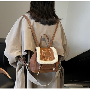 Close-up of brown faux leather backpack with white plush trim and FASHION logo detail