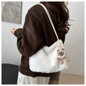 Detail of white plush crossbody bag with cute blue wave bear charm on a model