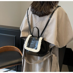 Detail shot of a black leather mini backpack with white faux fur trim on back of model