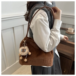 Detail view of plush brown tote bag with leather strap and cute lion charm accessory
