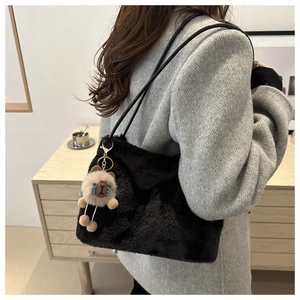 Detail of black faux fur tote bag with a cute bear pendant on a grey blazer outfit