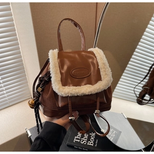 Detail of vintage brown faux suede backpack with sheepskin trim and embossed fashion logo