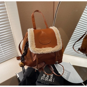 Close-up of vintage caramel brown faux suede backpack with white shearling trim and bell detail