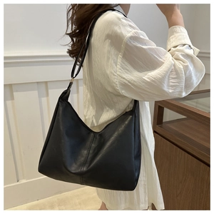 Detail of minimalist black leather tote bag with crescent shape and zip closure on shoulder