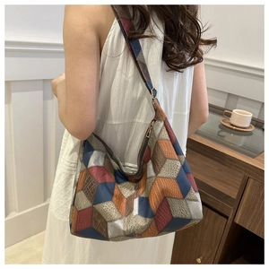 Detailed view of geometric patchwork hobo bag with colorful textures and gold zipper
