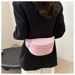 Sac banane en nylon rose porté sur un blazer noir pour un style décontracté chic