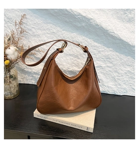 Brown leather hobo bag with vintage texture and adjustable strap in a lifestyle setting