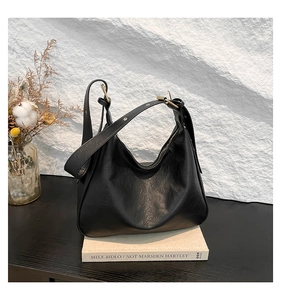 Close-up of black lychee texture leather tote featuring an adjustable wide strap and zipper