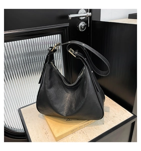 Detail of black leather tote bag with adjustable shoulder strap and gold hardware buckles