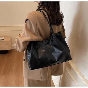 Side view of a large black tote bag on shoulder, showcasing minimalist PU leather texture